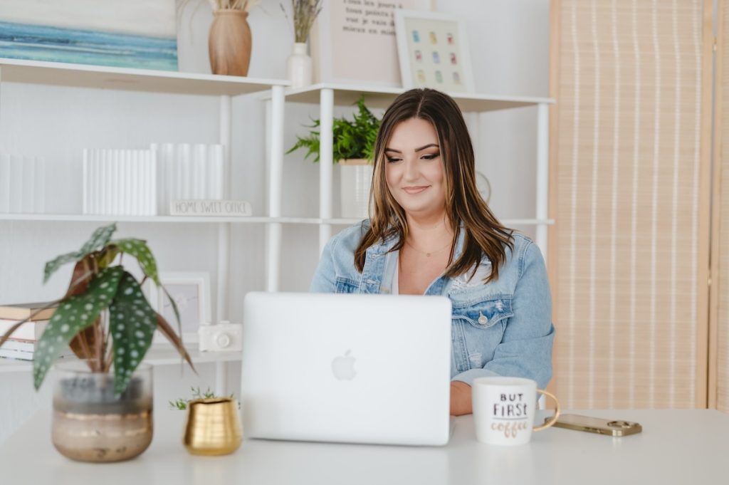 Female business owner sitting at a desk behind a laptop by Jen Vazquez Photography